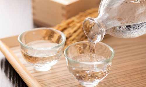 Pouring bottle of Awamori into glass